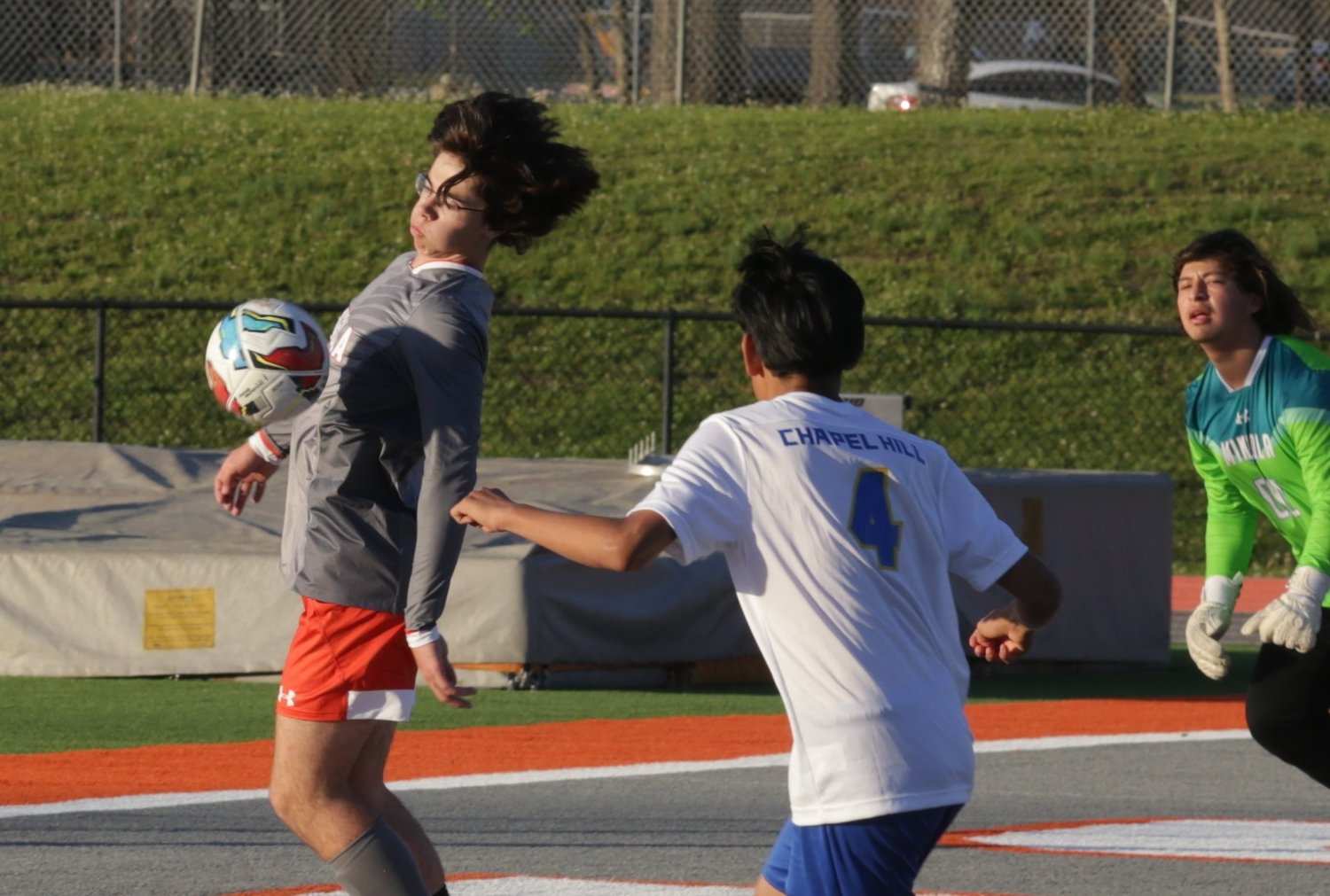 Kase Karch chests a ball down before clearing it off the Mineola line against Chapel Hill. Goalkeeper David Reyes is also pictured.